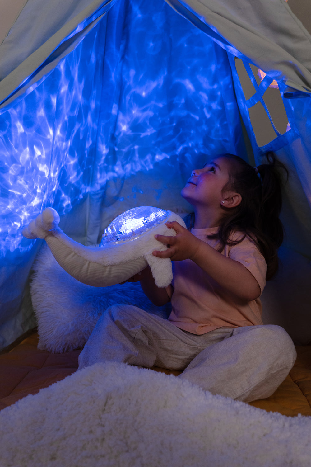 Child playing inside a lit playhouse with a whqale nightlight