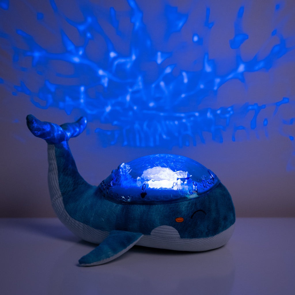 Whale-shaped night light projecting blue patterns on a wall