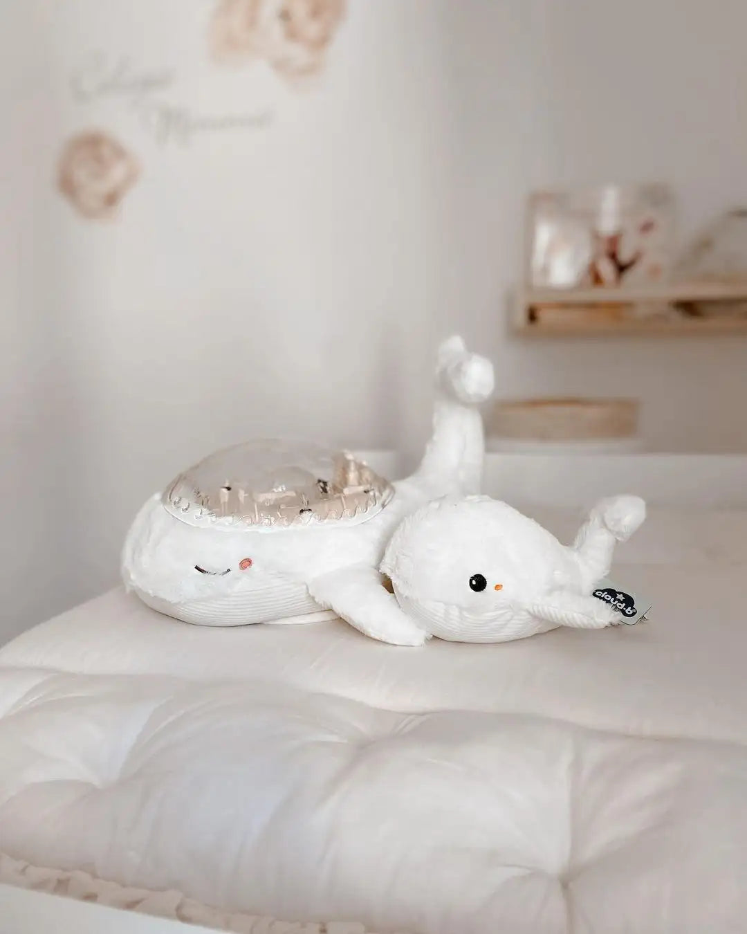 Two white plush toys resembling whales on a white surface with a neutral background
